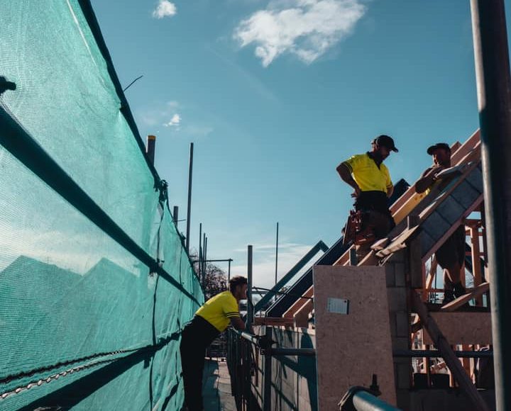 Blue Summit builders on roof framing of building site